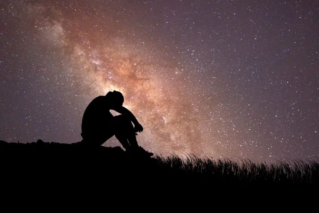 Silhouette d'un homme déprimé sur un fond de ciel étoilé.