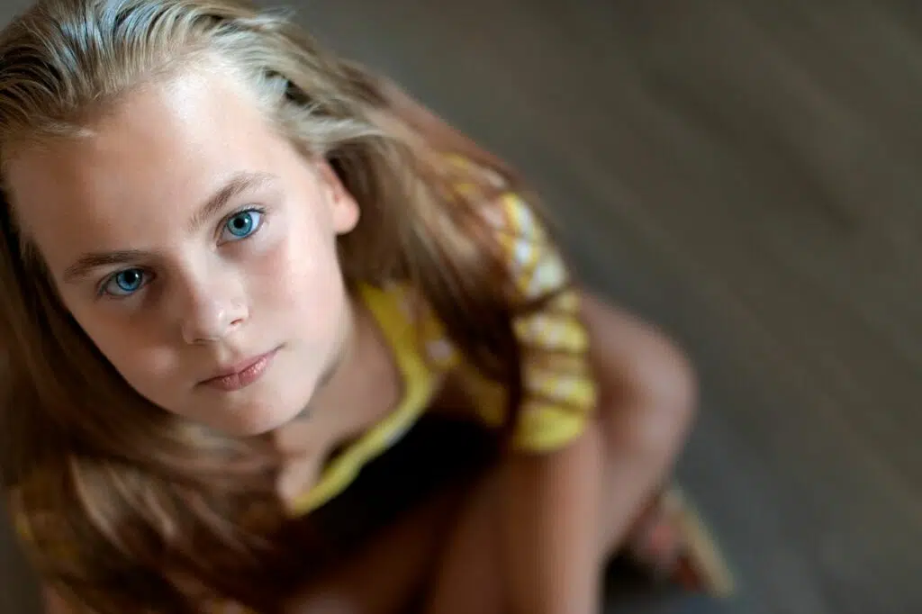 jeune fille blonde aux yeux bleus photographiée en plongée regardant vers le haut