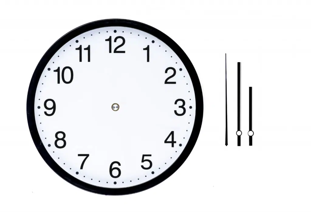 Illustration d'une horloge sans aiguille sur son cadrant. Les aiguilles sont représentées à droite du cadrant. 
