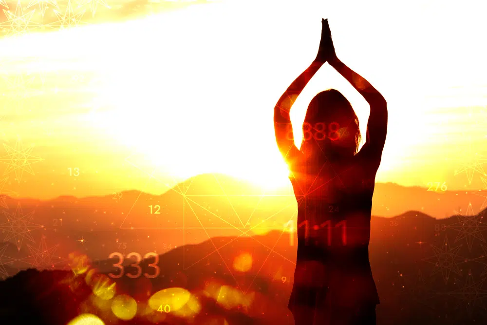 silhouette d'une femme qui joint ses mains au dessus de sa tête avec un coucher de soleil en arrière plan et des symboles de numérologie 